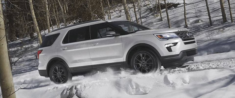 A white 2019 Ford Explorer driving through the snow