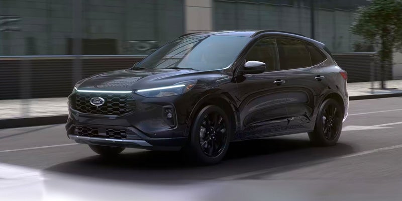 A silver 2024 Ford Escape driving down a city street