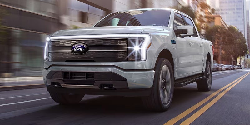 a white 2024f-150 lightning driving down a city street