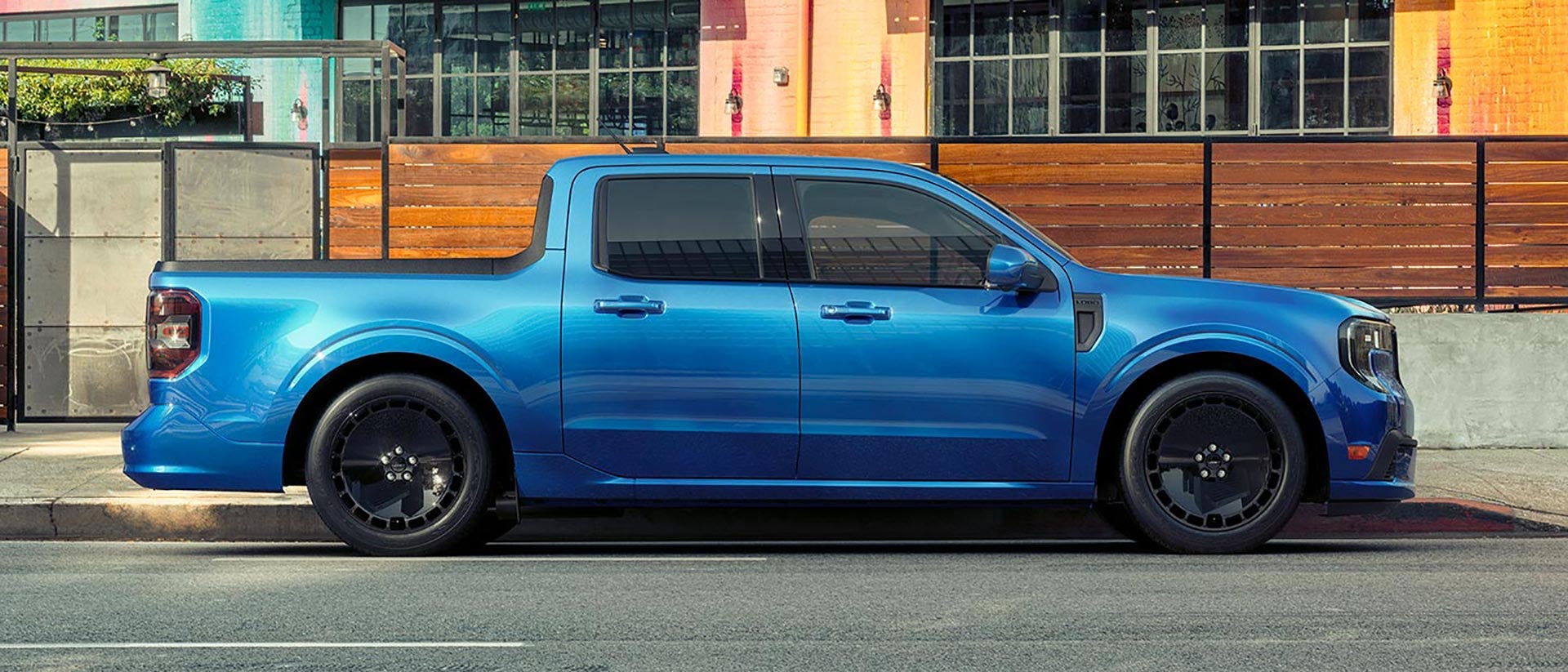 Profile view of a blue Ford Maverick® Lobo™ pickup parked in front of a restaurant patio