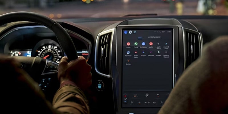 view of a man driving a 2024 Ford Edge at night time utilizing the vehicle's safety features displayed on the SUV's infotainment screen