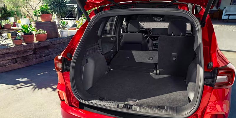 rear view of the trunk and folded down rear passenger seats in a red 2024 Ford Escape that is parked in a residential driveway