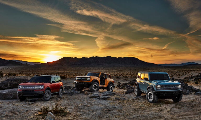 Three 2023 Ford Broncos parked in desert at sunset