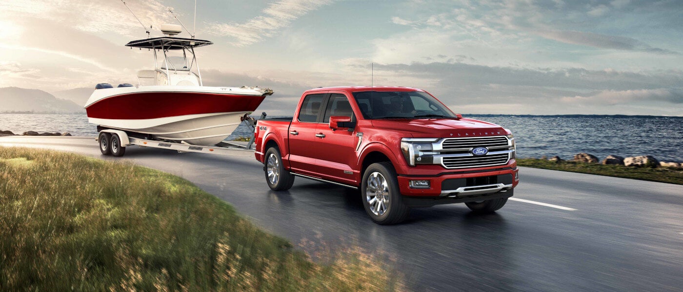 2024 Ford F-150 driving lakeside towing a boat