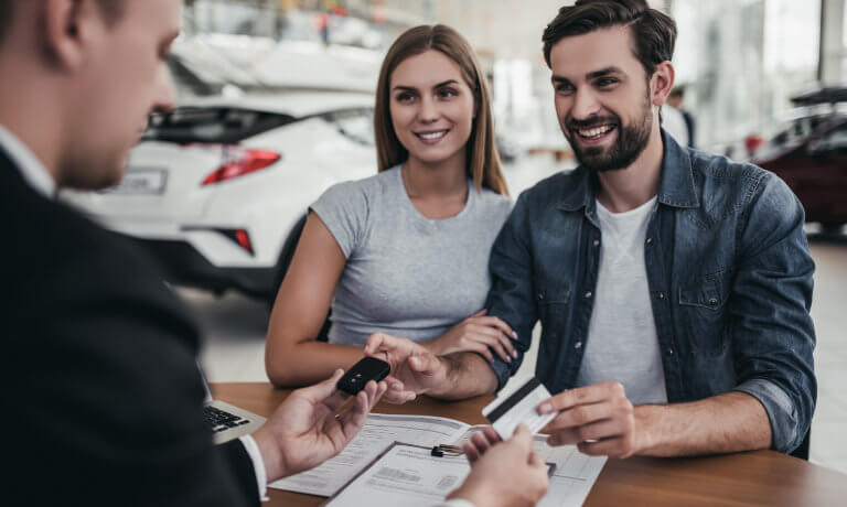 Couple making a deal with a car salesman