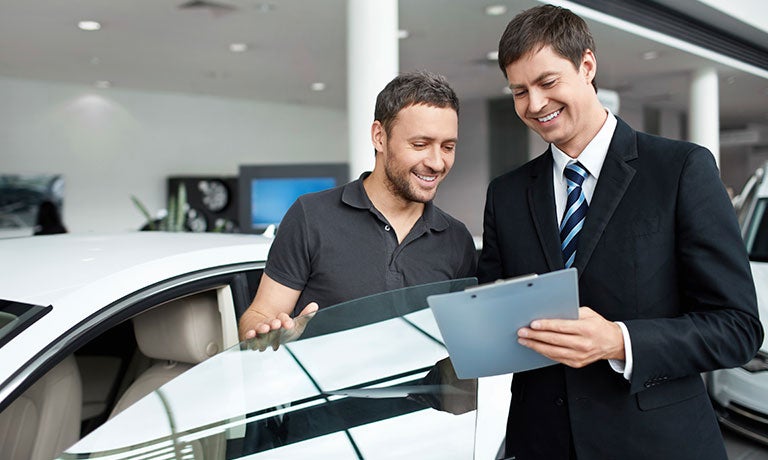 Men looking at clipboard beside car